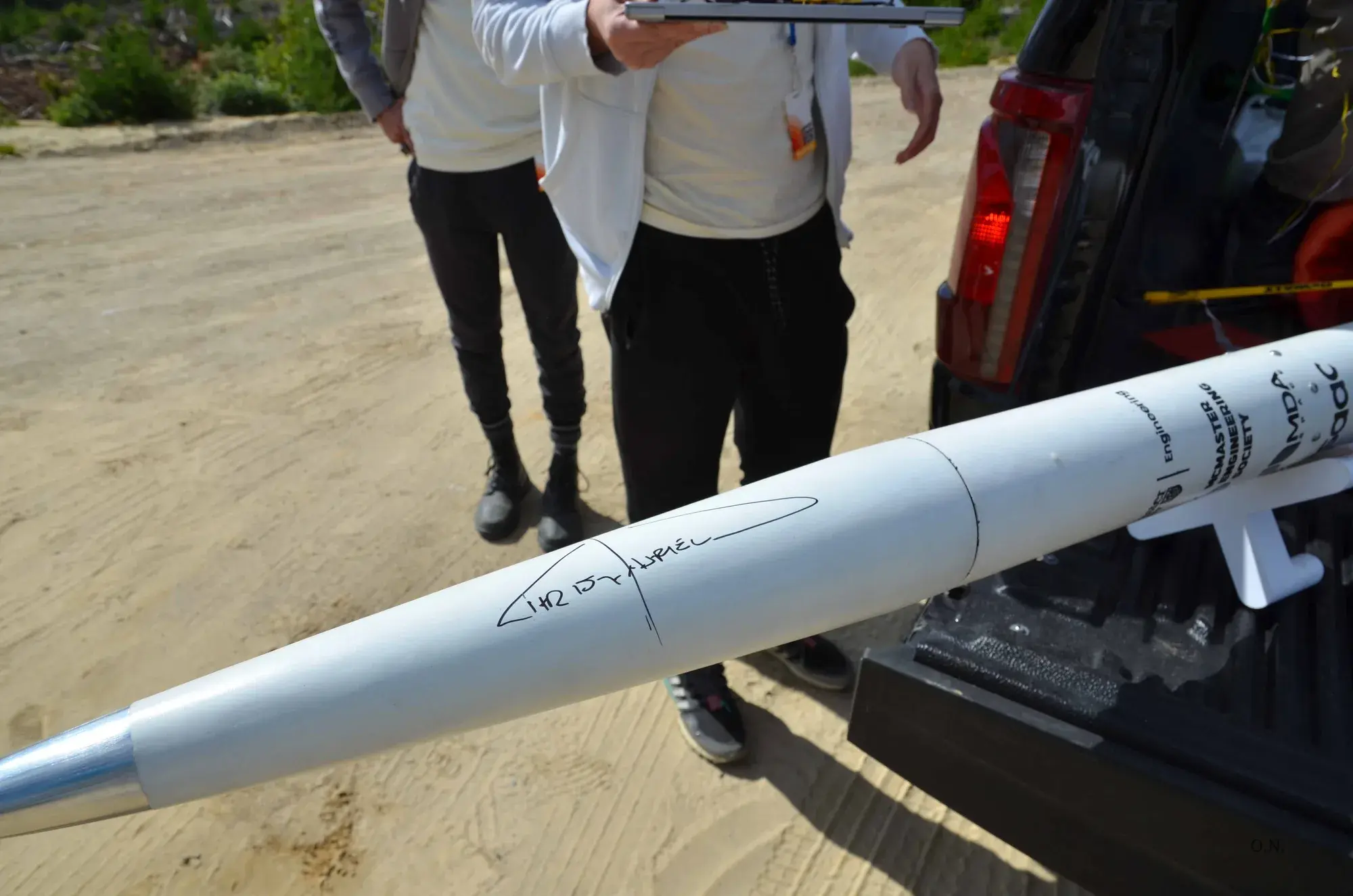 Osiris's white nosecone with Chris Hadfield's signature in black marker, resting on a truck tailgate.