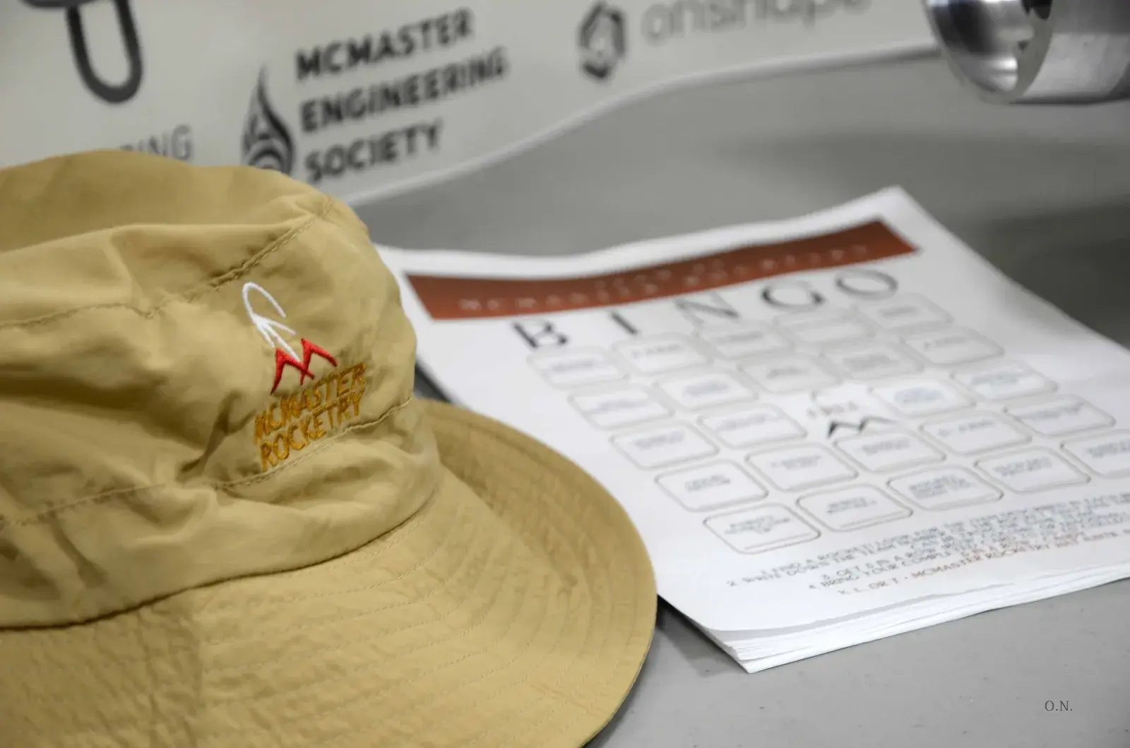 A McMaster Rocketry bucket hat beside a stack of rocketry bingo cards on a table at Launch Canada 2026.