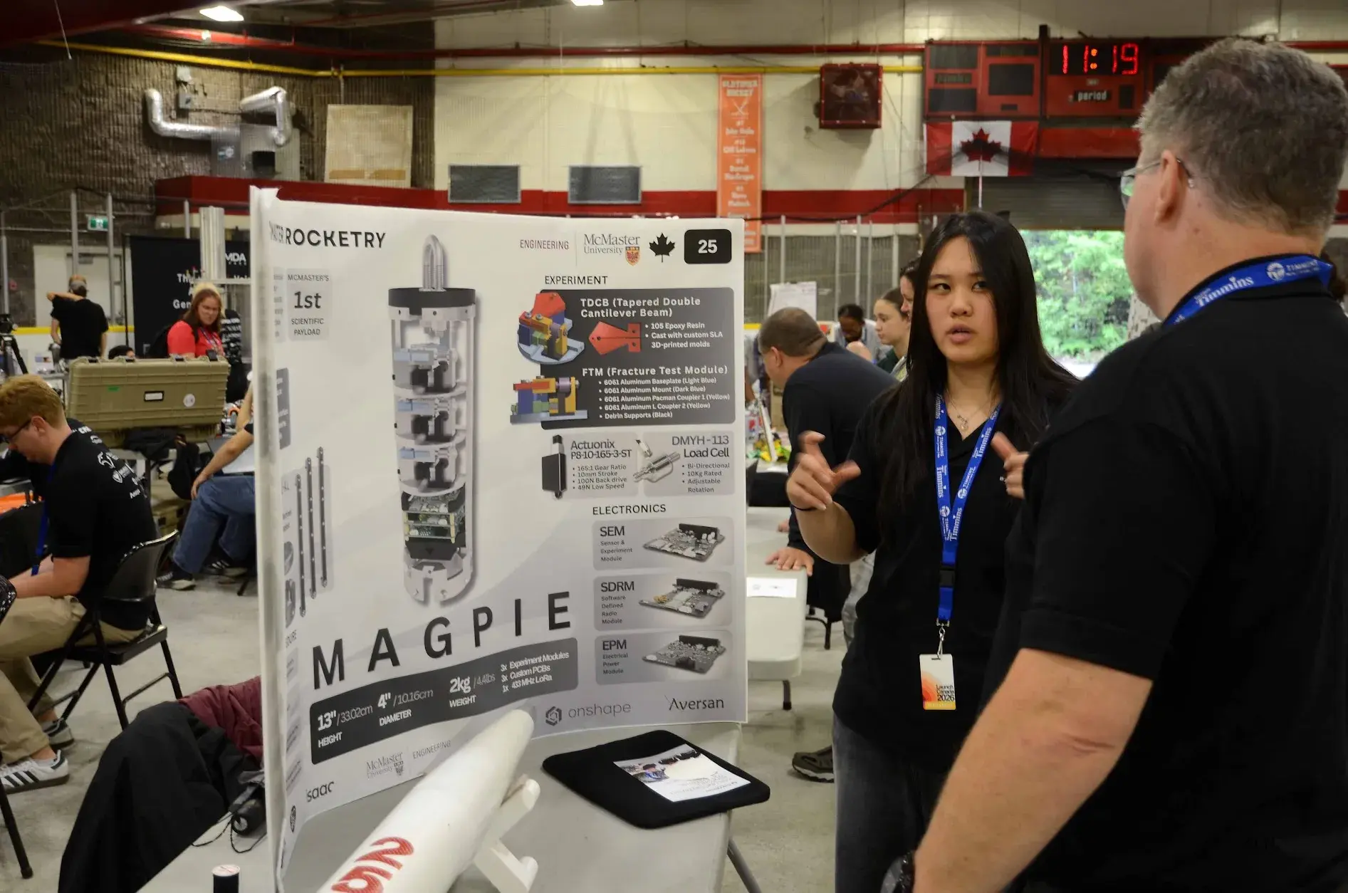 A team member presents the Magpie competition poster at the McMaster Rocketry booth.