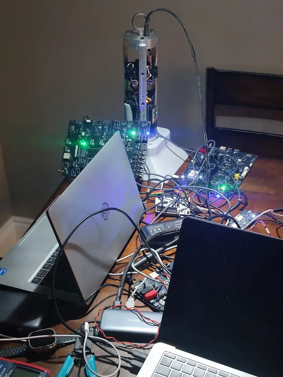 Top-down view of Sparrow on the workbench surrounded by SRAD PCBs, laptops, and test gear.