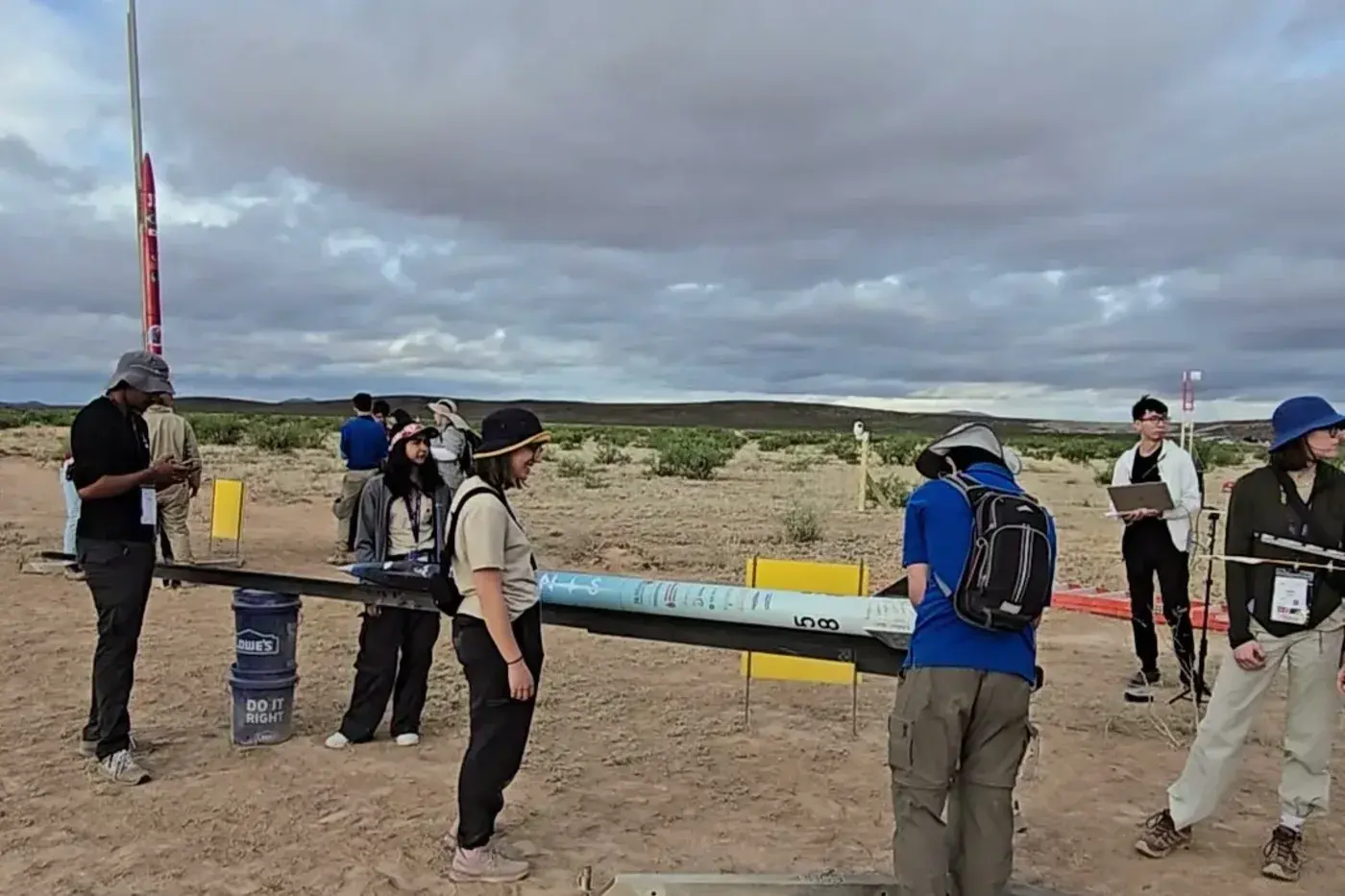 Luminis lies horizontal on the launch rail at Spaceport America Cup, team 58 making final checks before flight.