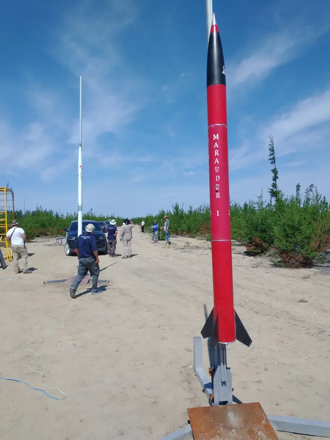 Marauder I stands vertical on the rail in the sandy clearing before launch.