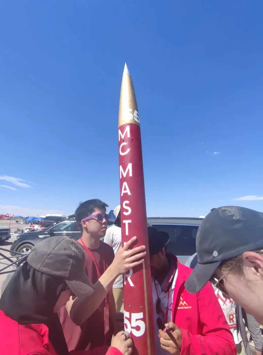 The Marauder II team holds the airframe at Spaceport America Cup 2023, bib 55 and McMaster lettering readable.