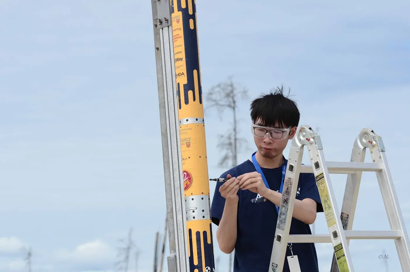 A team member arms Nimbus on the launch rail against clear sky before flight.