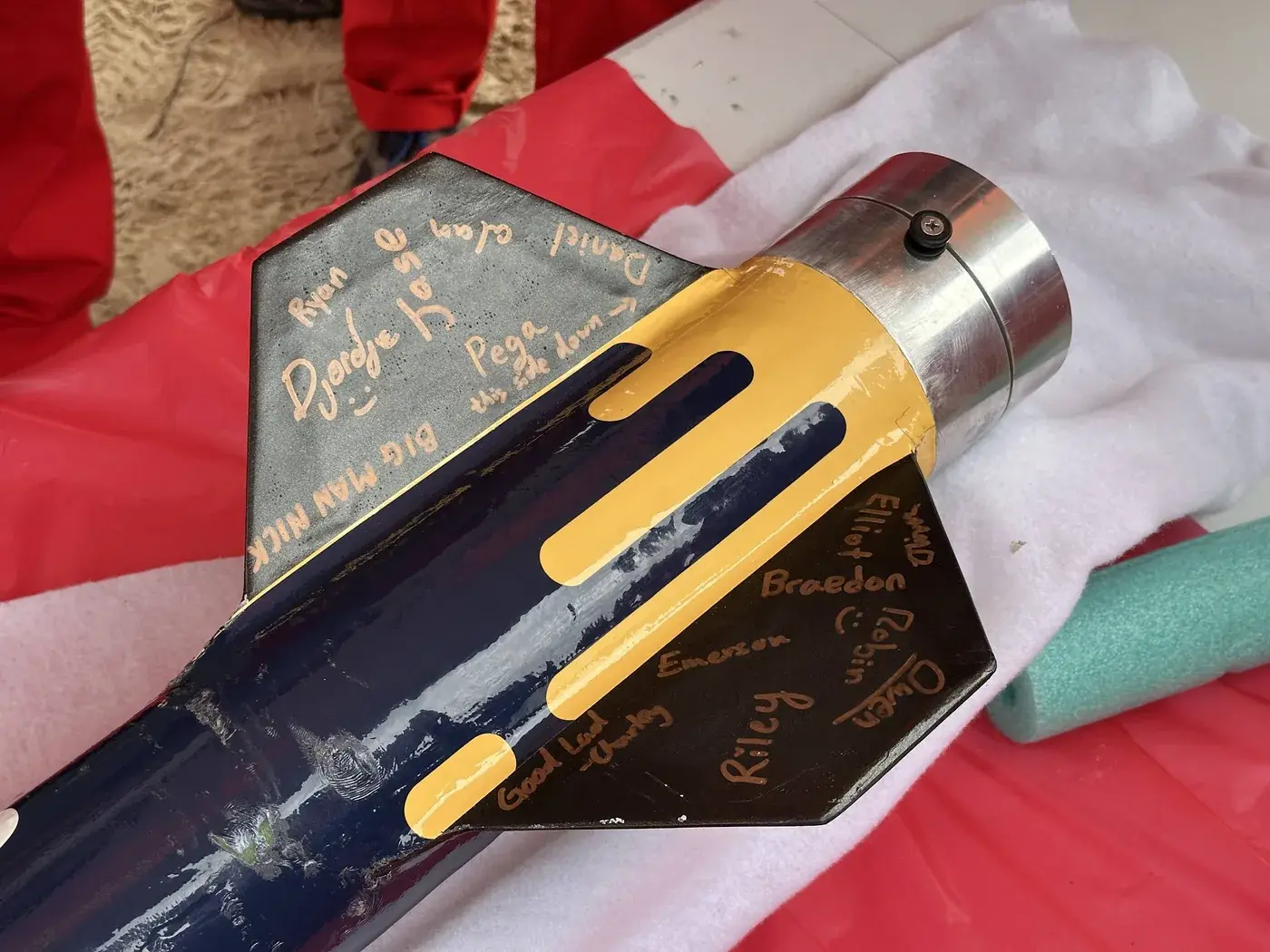 Signed Nimbus fin sections on a towel after recovery, team names in gold marker.