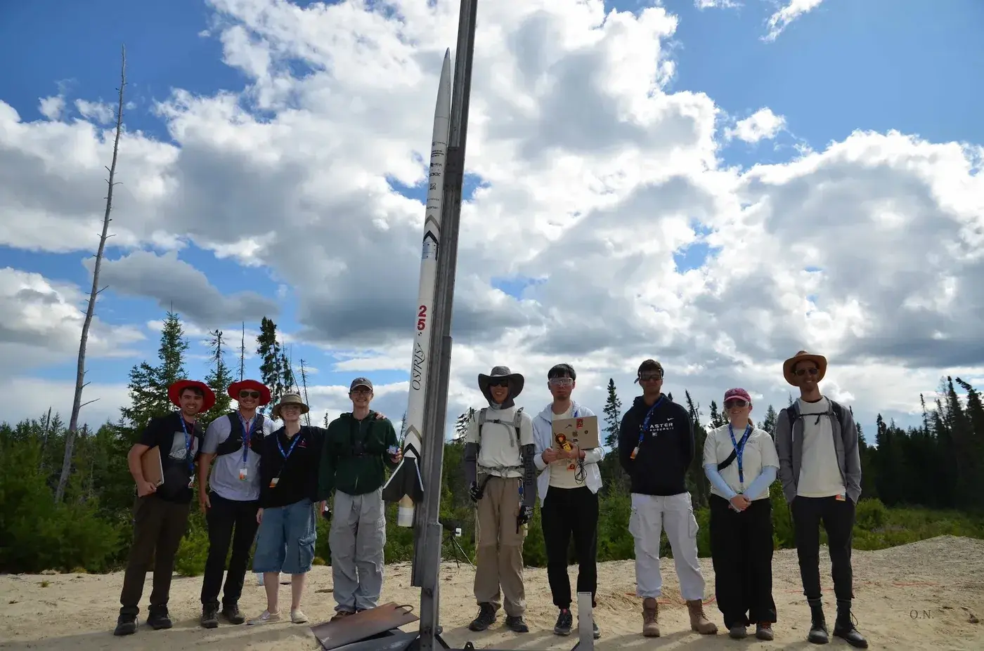 The team stands beside Osiris, vertical on the rail, before launch.