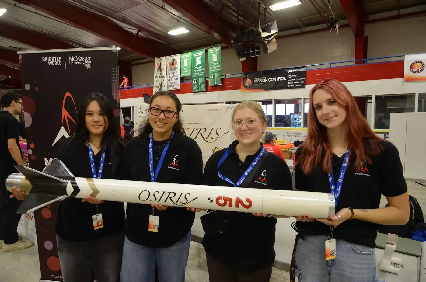 Four team members hold the assembled Osiris airframe, OSIRIS lettering and bib number 25 visible, at the competition venue.